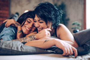 Two women cuddling and laughing in bed